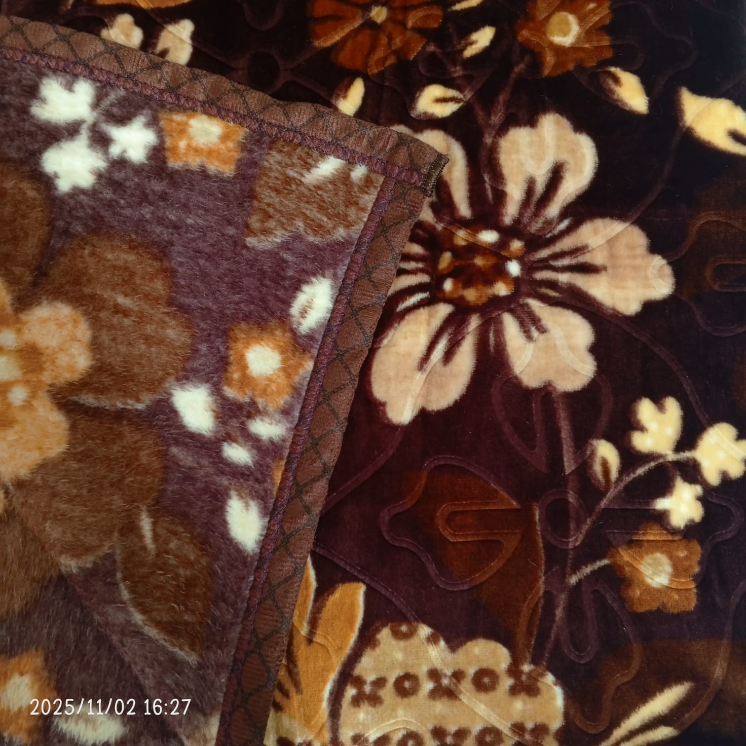 Soft brown floral blanket with bold beige and gold flower patterns, close-up view